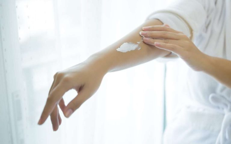 Mulher segurando creme cosmético após depilação a laser